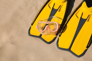 Photo of Pair of flippers and diving mask on sandy beach, above view