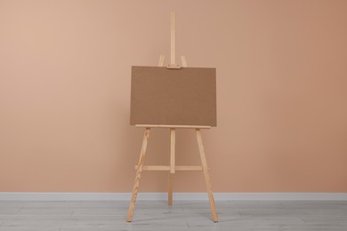 Wooden easel with blank board near beige wall indoors