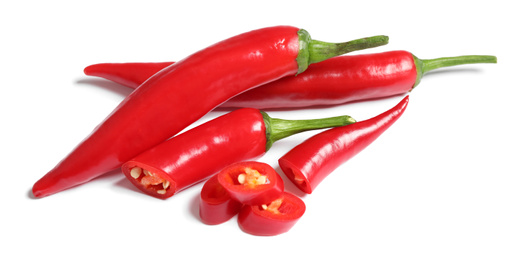 Photo of Cut and whole red hot chili peppers on white background