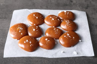 Photo of Tasty caramel candies and salt on grey table