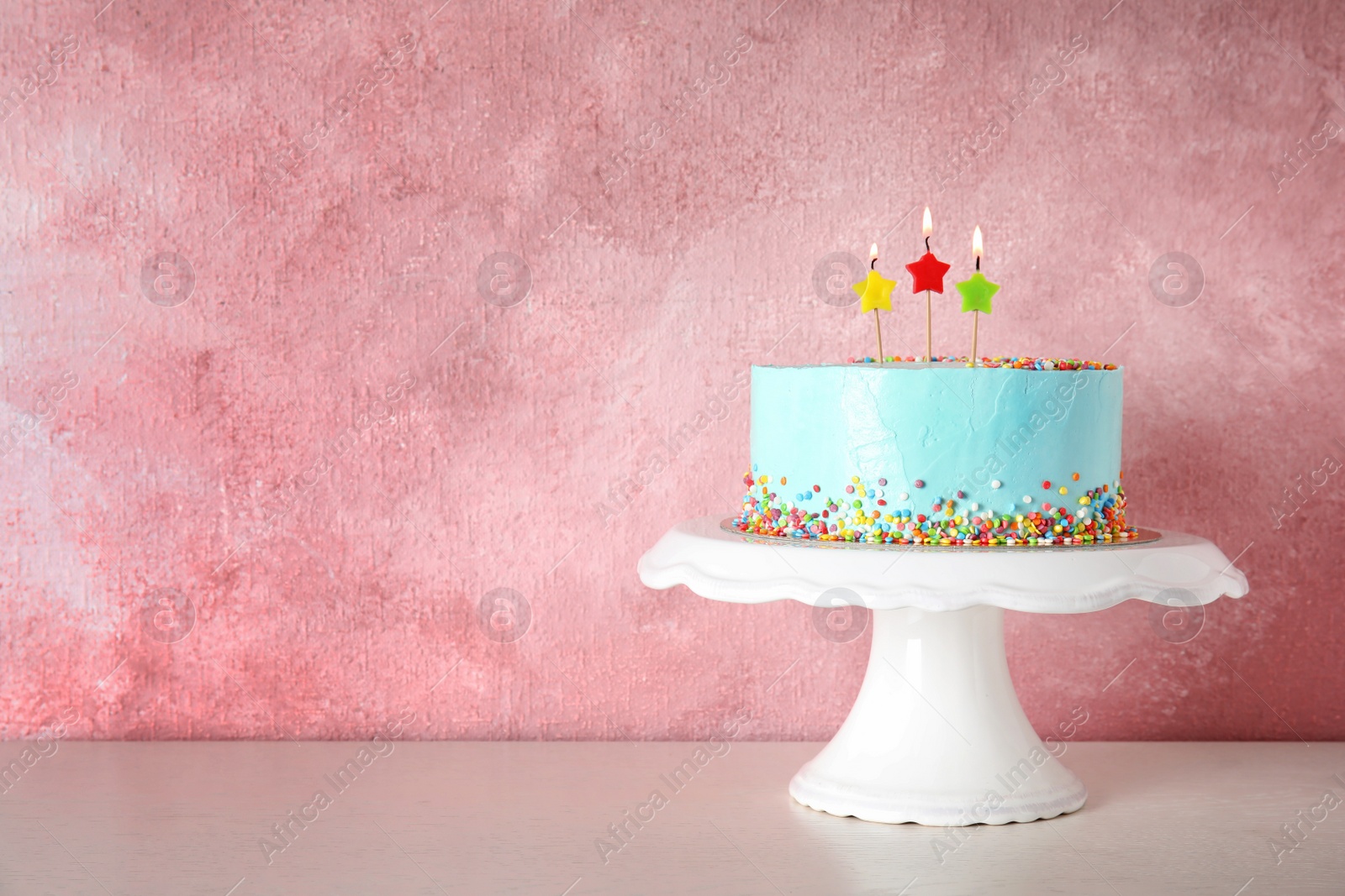 Photo of Fresh delicious birthday cake with candles on stand against color background. Space for text