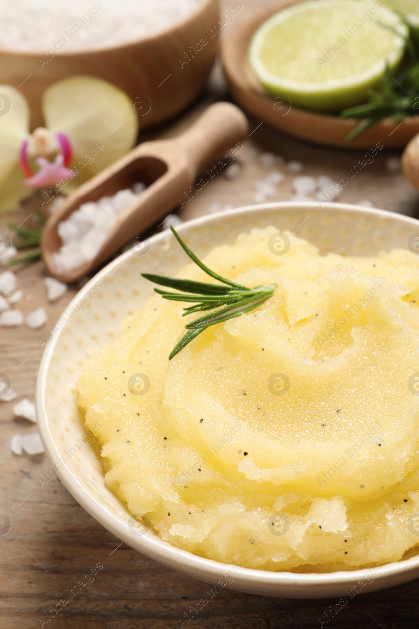 Photo of Body scrub with rosemary in bowl on wooden table, closeup