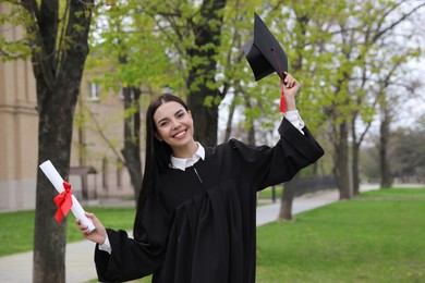 Photo of Happy student with diploma after graduation ceremony outdoors