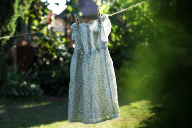 Photo of Dress drying on washing line near trees outdoors