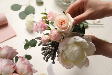 Photo of Florist creating beautiful bouquet at white table, closeup