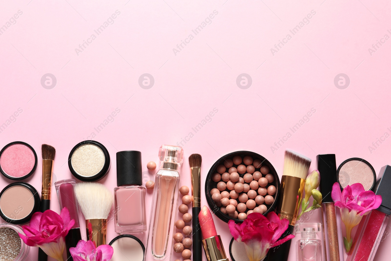 Photo of Different makeup products with flowers on color background. Space for text