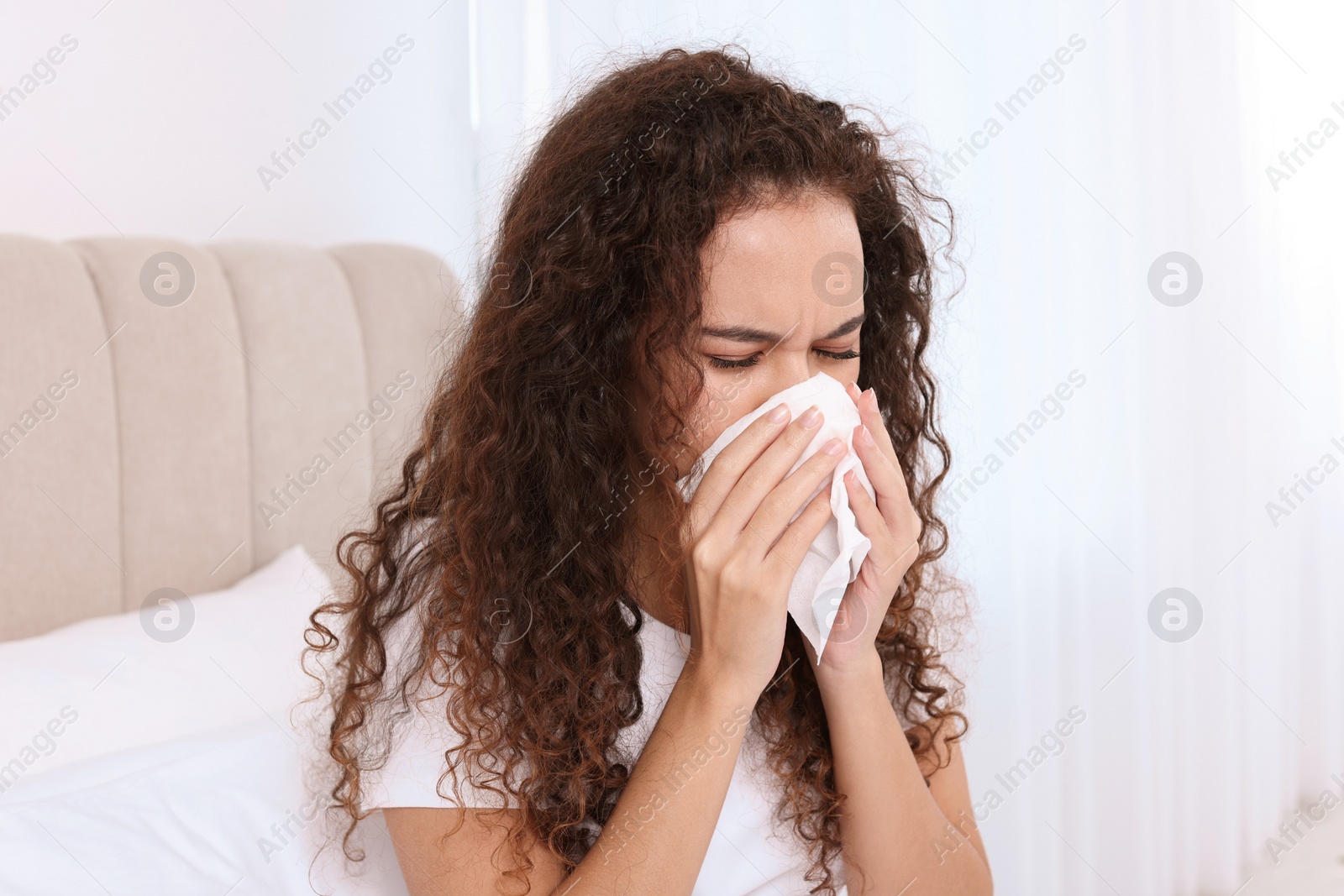 Photo of Sick African American woman with tissue in bed at home