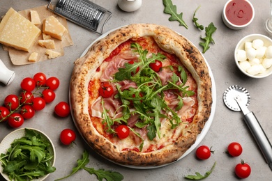 Photo of Tasty pizza with meat and arugula on grey table, flat lay