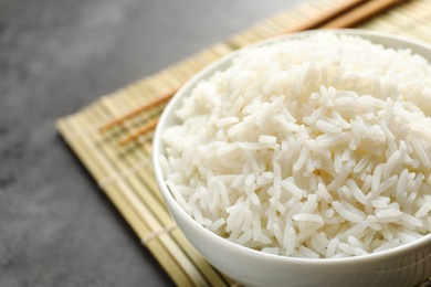 Bowl of tasty cooked rice served on table, closeup. Space for text