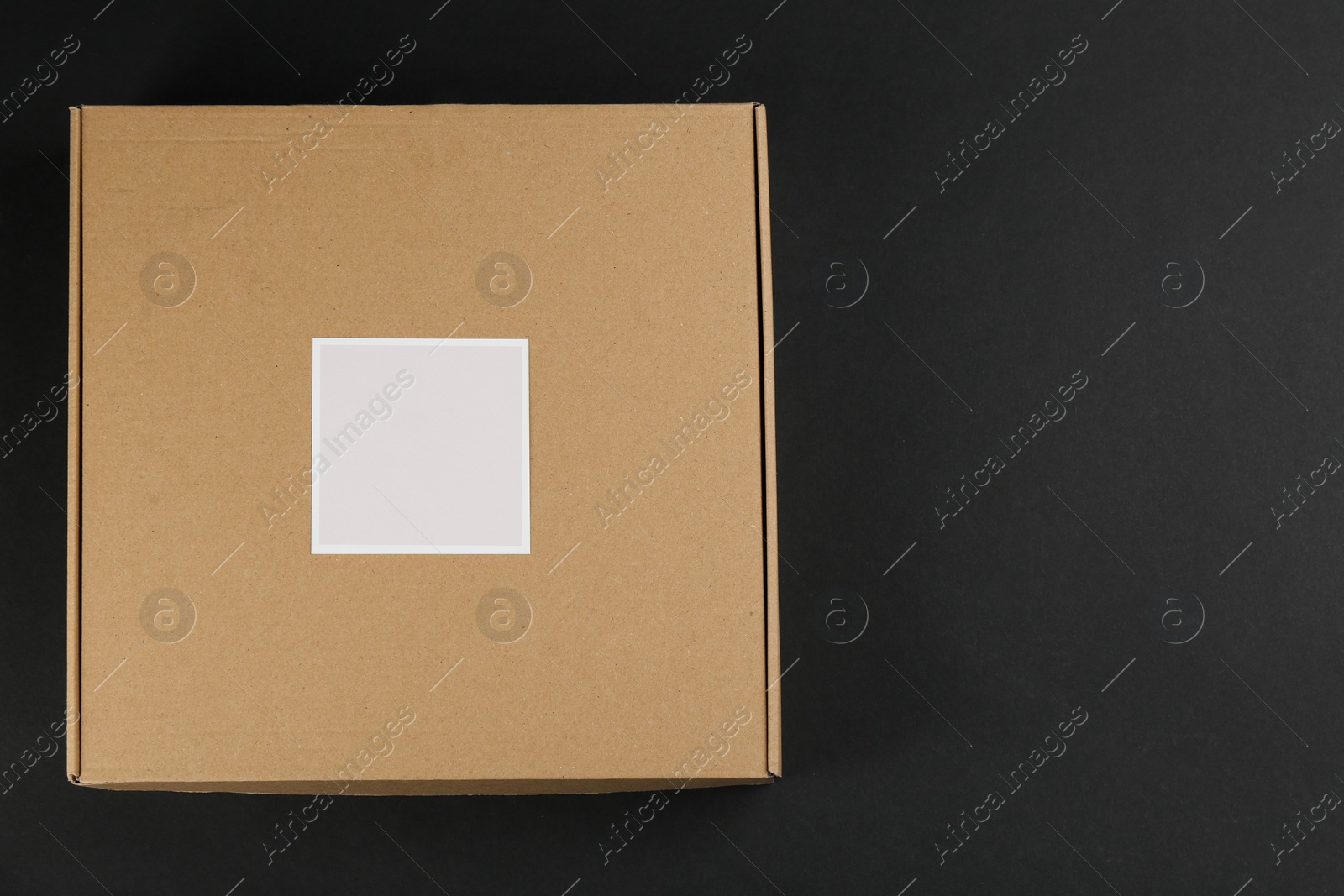 Photo of Cardboard box on black background, top view. Space for text