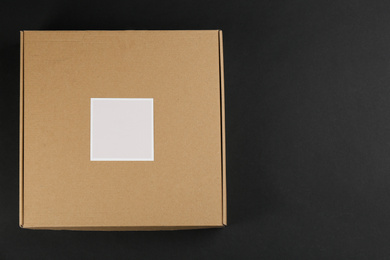 Photo of Cardboard box on black background, top view. Space for text