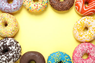 Photo of Delicious glazed donuts on yellow background, flat lay. Space for text