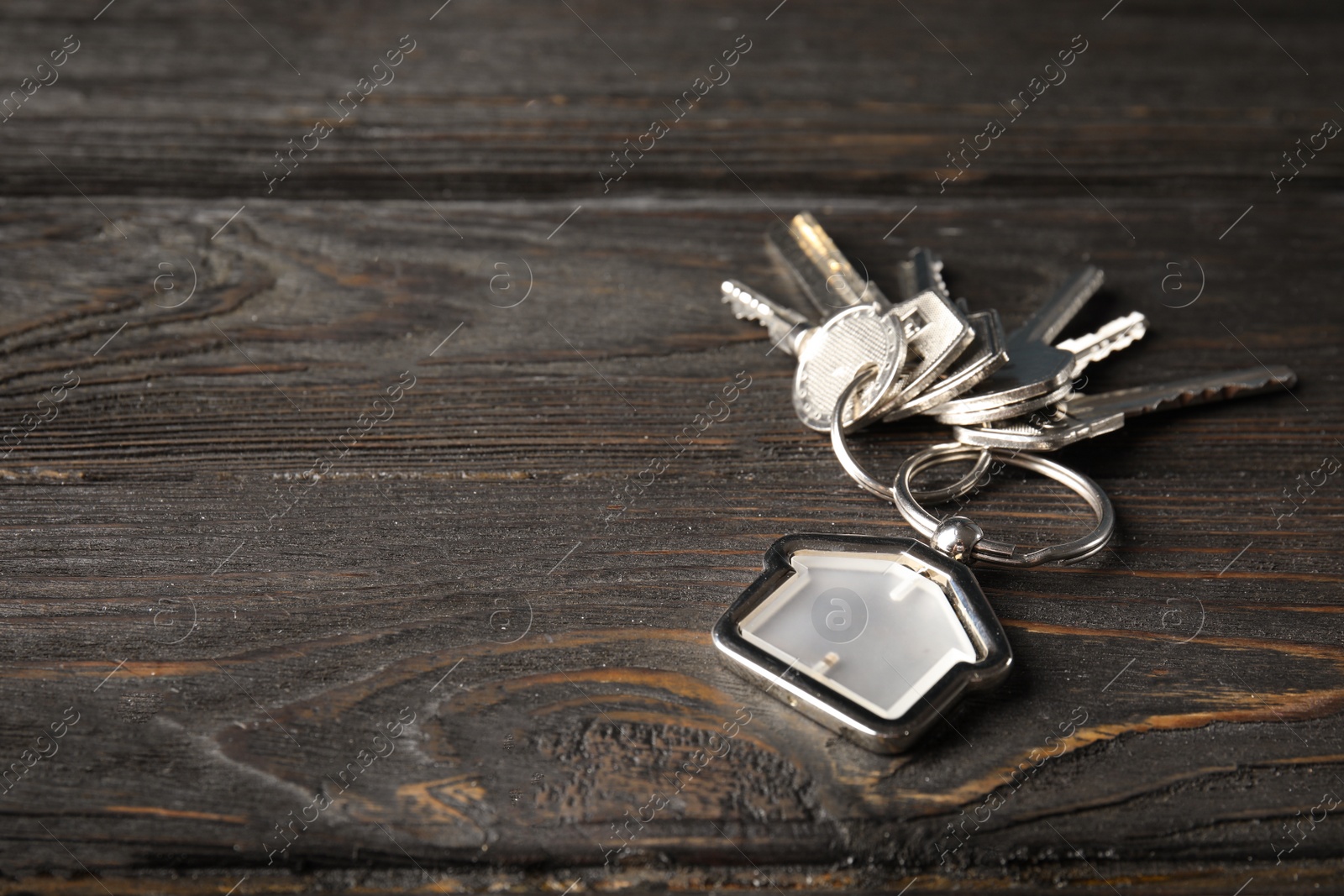 Photo of Bunch of house keys and trinket on wooden background. Space for text