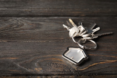 Photo of Bunch of house keys and trinket on wooden background. Space for text