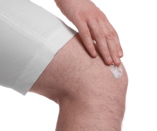 Man applying ointment onto his knee on white background, closeup