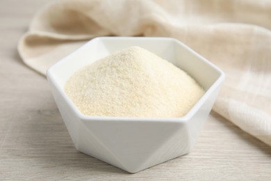 Photo of Gelatin powder in bowl on white wooden table, closeup