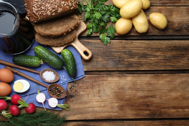 Flat lay composition with kvass and other okroshka ingredients on wooden table, space for text. Traditional Russian summer soup