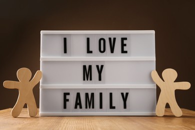 Photo of Wooden figures and lightbox with phrase I Love My Family on table