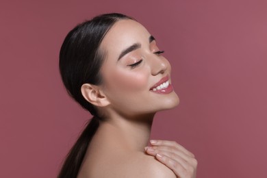 Photo of Portrait of beautiful young woman with perfect makeup on dark pink background