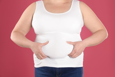 Overweight woman on color background, closeup. Obesity and weight loss