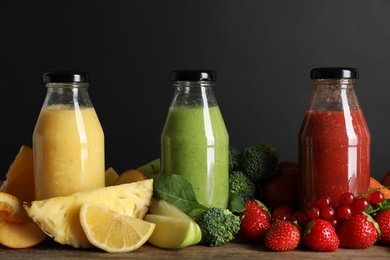 Photo of Bottles of delicious juices and fresh fruits on wooden table