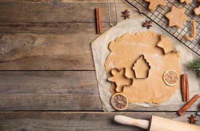 Making homemade Christmas cookies. Flat lay composition with dough and cutters on wooden background, space for text