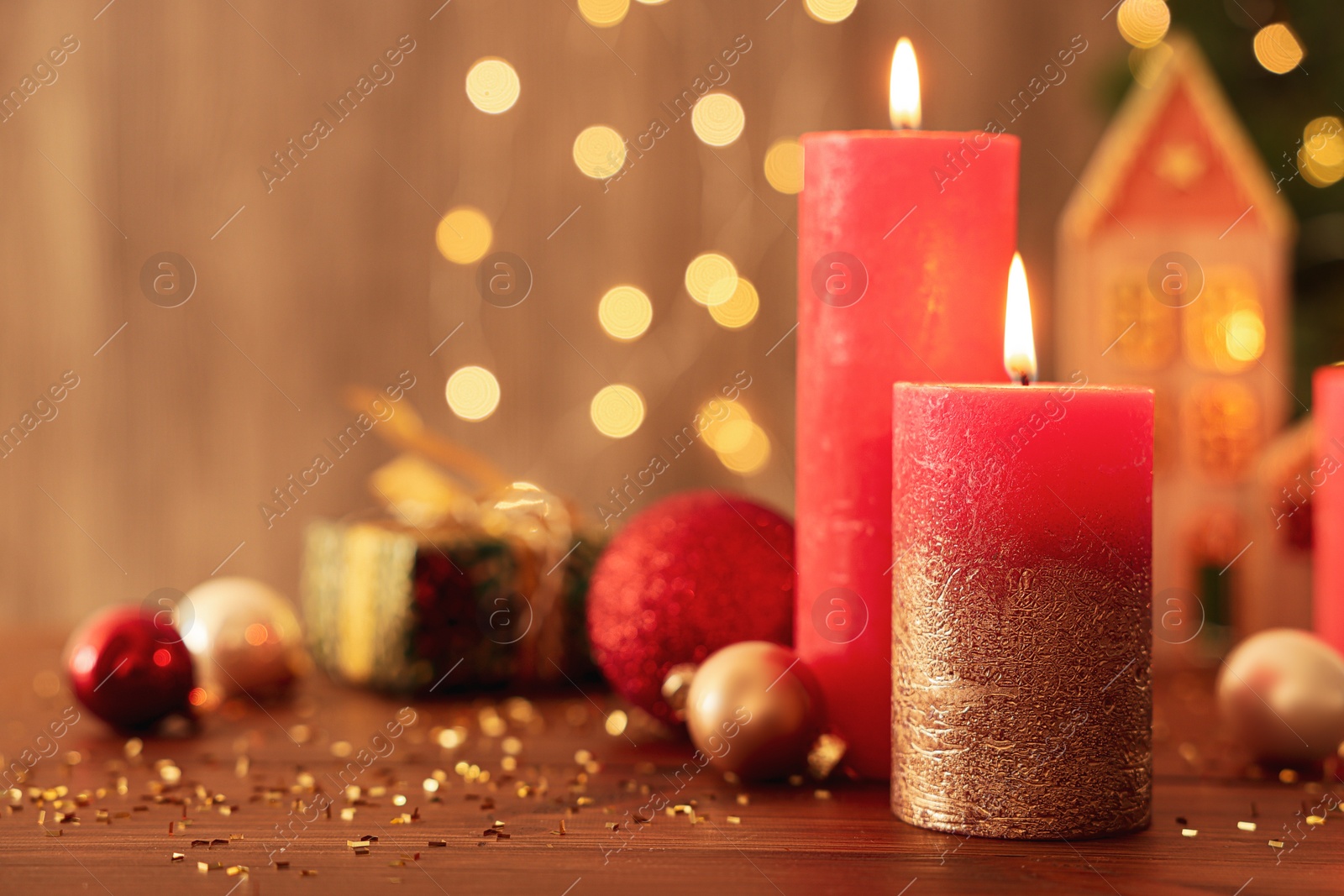 Photo of Beautiful burning candles with Christmas decor on wooden table against blurred festive lights, space for text