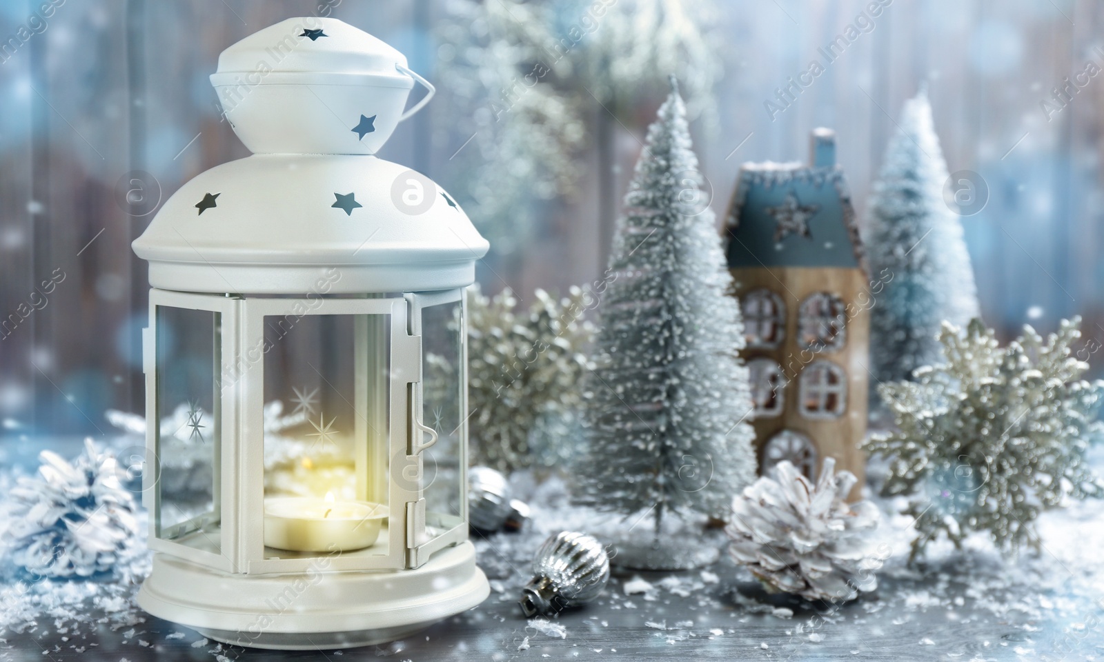 Image of Christmas lantern with burning candle and festive decor on wooden background