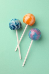 Photo of Tasty lollipops on turquoise background, flat lay