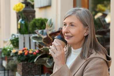 Photo of Beautiful senior woman sitting in outdoor cafe and drinking coffee, space for text