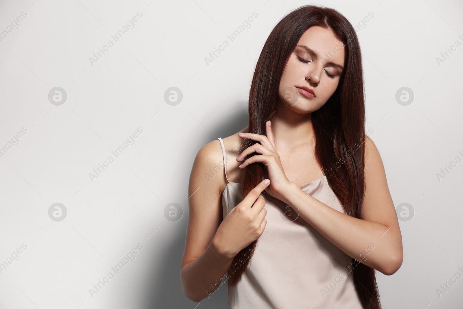 Photo of Portrait of beautiful young woman with healthy strong hair on light gray background, space for text