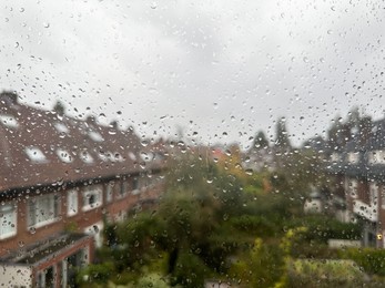 Photo of View on city street through window with water droplets on rainy day, closeup