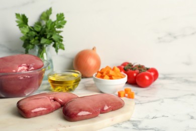 Photo of Fresh raw pork kidneys and ingredients on white marble table, space for text