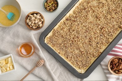 Making delicious baklava. Baking pan with dough and ingredients on white table, flat lay