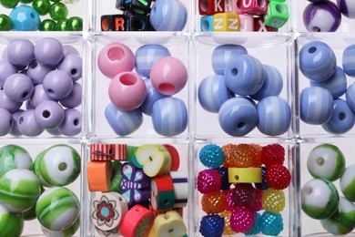 Plastic organizer with different beads as background, top view