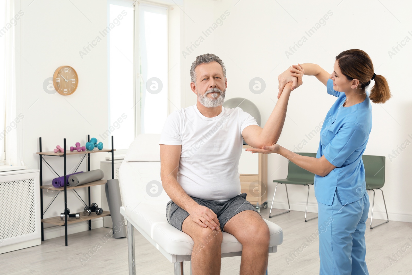 Photo of Physiotherapist working with patient in clinic. Rehabilitation therapy