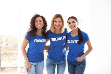 Portrait of happy female volunteers in uniform indoors