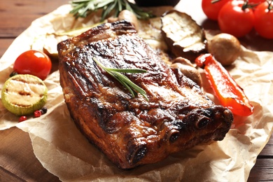 Photo of Delicious ribs served with vegetables for barbecue party on wooden table