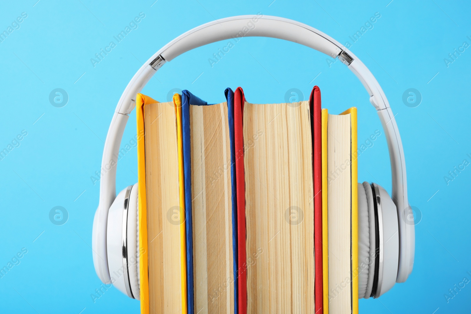 Photo of Books and modern headphones on light blue background