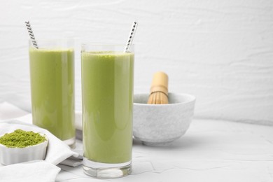 Glasses of tasty matcha smoothie and powder on white table, space for text