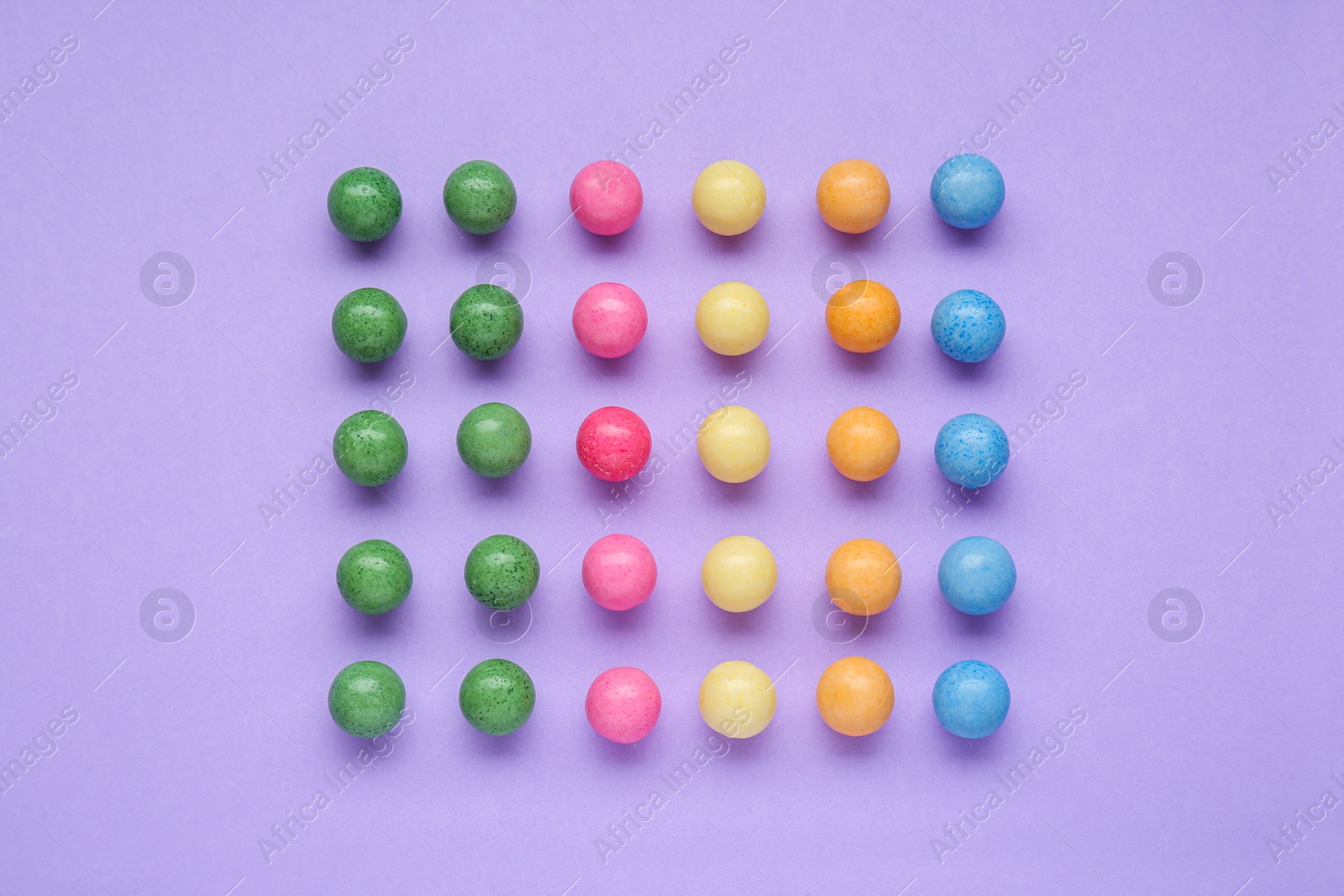 Photo of Many bright chewy gumballs on lilac background, flat lay