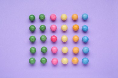 Photo of Many bright chewy gumballs on lilac background, flat lay
