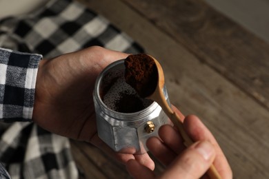 Man putting ground coffee into moka pot at table, above view