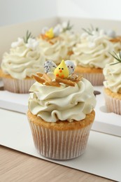 Tasty Easter cupcakes in box on wooden table, closeup