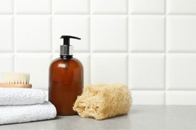 Photo of Different bath accessories and cosmetic bottle on gray table near white tiled wall, space for text