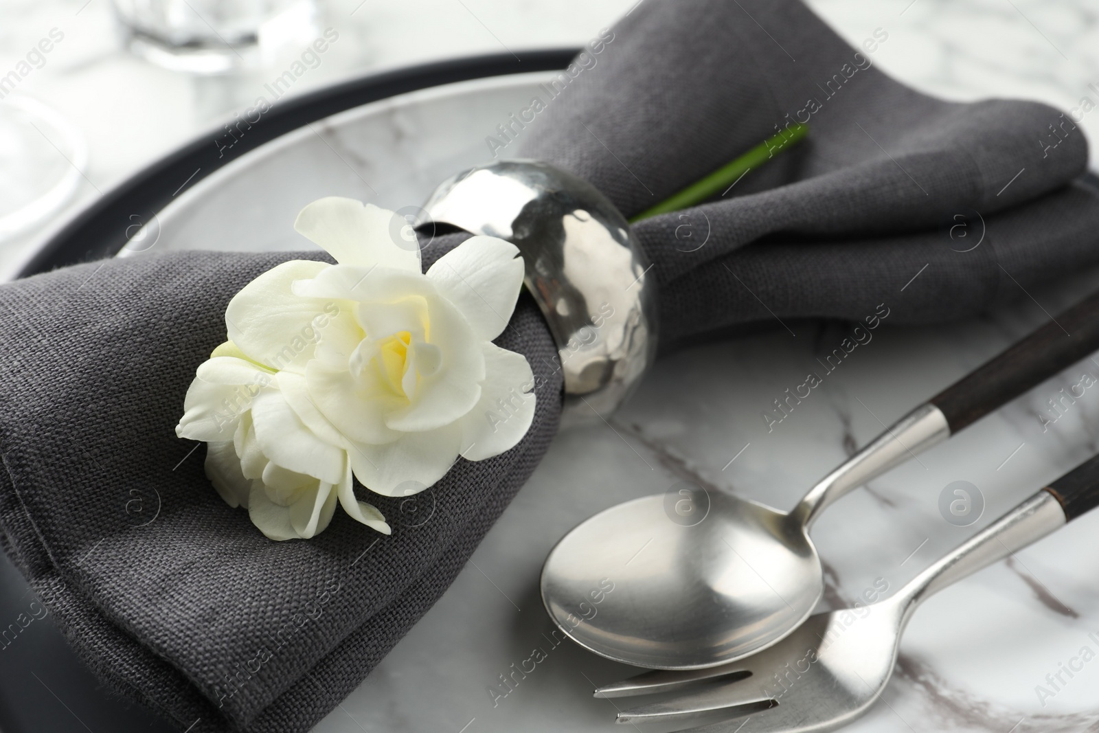 Photo of Stylish setting with cutlery, napkin, flowers and plates on table, closeup