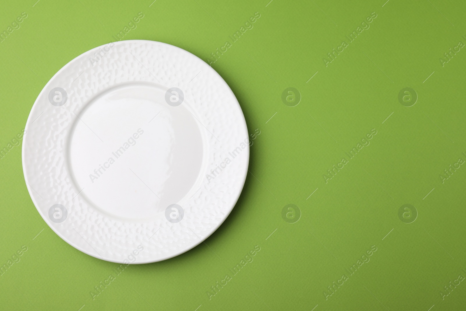 Photo of One clean plate on green background, top view. Space for text