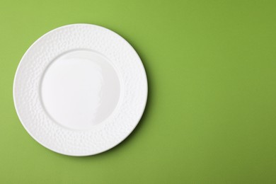 Photo of One clean plate on green background, top view. Space for text