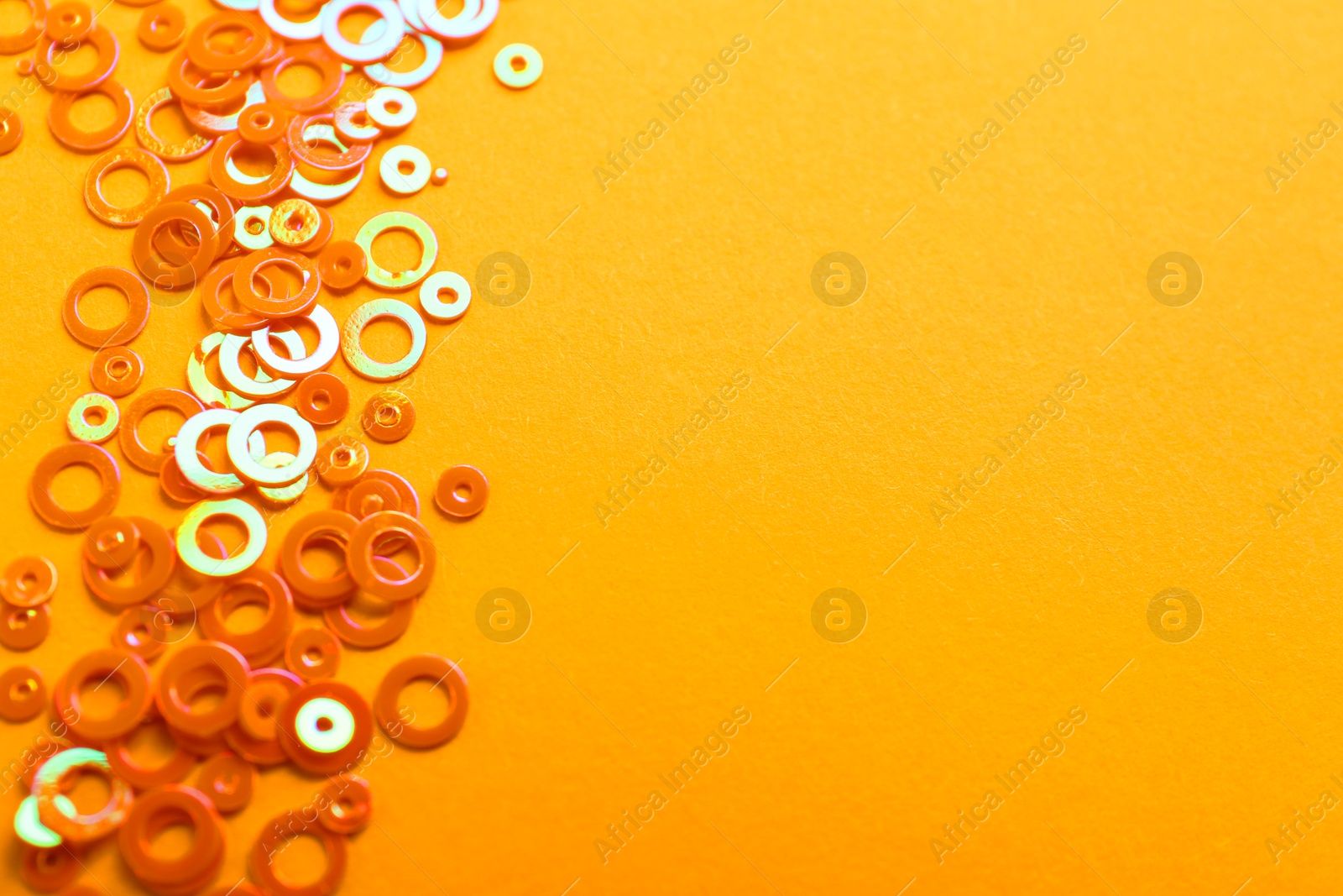 Photo of Shiny bright glitter on pale orange background. Space for text