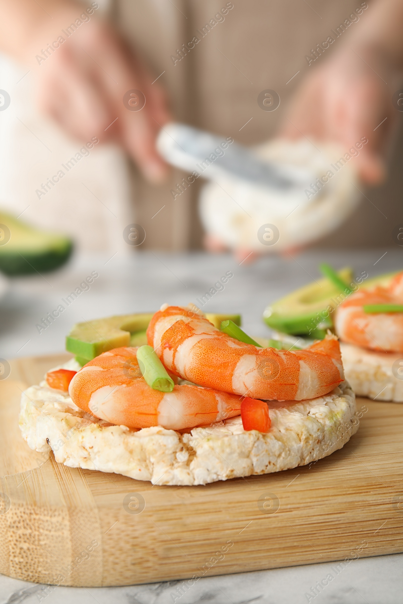 Photo of Puffed rice cake with shrimps and avocado on wooden board, closeup